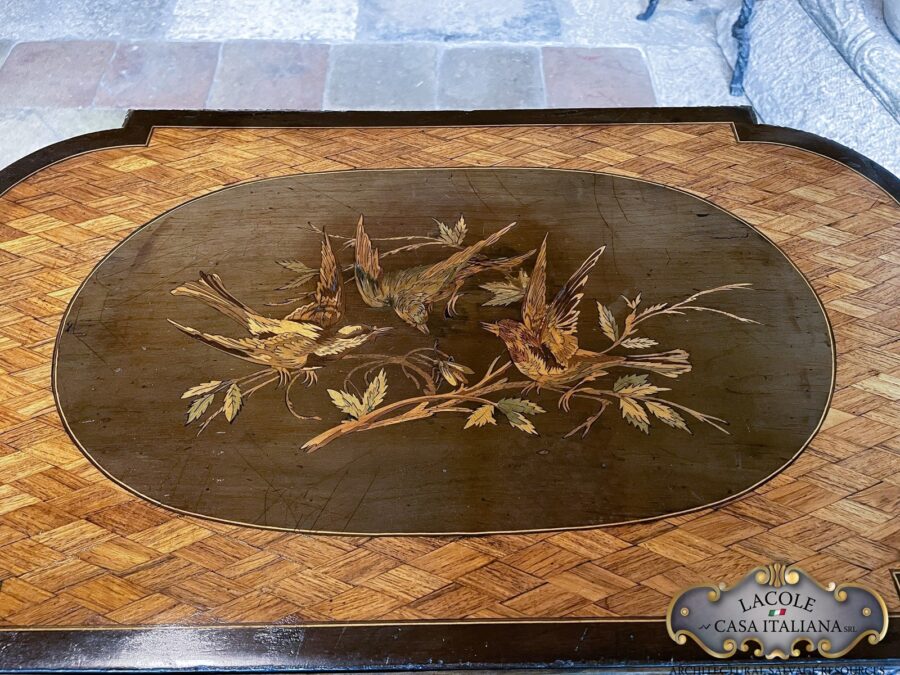 <h2>Tavolino antico da lavoro.</h2> <em>Tavolino antico da lavoro</em> con gamba a lira; intarsi con legni pregiati e bronzi a rilievo. Epoca primi 1800.