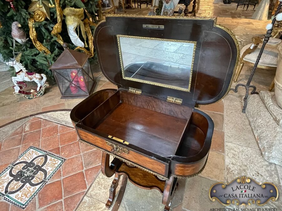 <h2>Tavolino antico da lavoro.</h2> <em>Tavolino antico da lavoro</em> con gamba a lira; intarsi con legni pregiati e bronzi a rilievo. Epoca primi 1800.