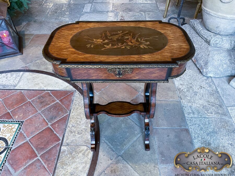 <h2>Tavolino antico da lavoro.</h2> <em>Tavolino antico da lavoro</em> con gamba a lira; intarsi con legni pregiati e bronzi a rilievo. Epoca primi 1800.